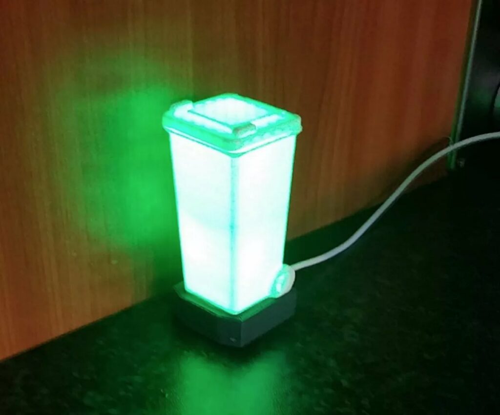 A small plastic refuse bin which is lit up green signifying the bin to take out this week.